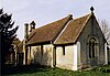 A simple rendered church with a red tiled roof and a bellcote