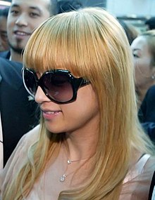 A woman with long blonde hair and large sunglasses in a crowd.