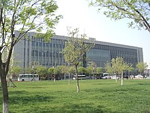 a low rise concrete-and-glass building partially obscured by trees