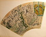 Fan shaped paper with text in Chinese script over a painting of a man, a woman and plants.