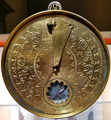 Circular brass time measurement device with engraved Arabic toponyms and zodiac symbols.