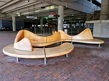 A wavy wooden bench inside a parking garage