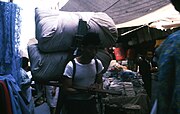 Man carrying things on his back through the market's narrow streets (1968)
