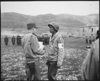 阿尔方斯·朱安授予一名医护兵英勇十字勋章，以纪念其尽管在意大利战场上受伤仍然完成任务。