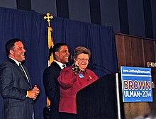 Barbara Mikulski speaks at a podium with a Brown-Ulman campaign sign while Ulman and Brown stand behind her