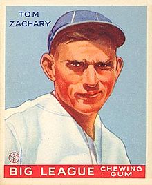 A baseball card image of a severe-looking man wearing a white baseball jersey and a blue baseball cap