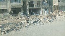 Destroyed section of a street in front of two buildings