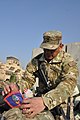 A soldier of the Guam Army National Guard attaches a miniature Guam flag to his carry-on bag