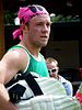 A South African cricketer wearing green T-shirt and carrying his pads. Others can be seen in background.