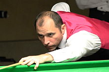 Joe Perry leaning across a snooker table preparing to take a shot