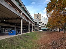 A depressed grassy area and trees next to a large parking garage