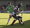 A Kingstonian player (in red and white) shields the ball