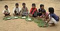 Schoolchildren in Chambal, Madhya Pradesh eating a mid-day meal. The Mid-Day Meal Scheme attempts to lower rates of childhood malnutrition in India.