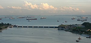 Marina Barrage viewed from the south eastern end. In the foreground is the Marina Reservoir separated by the dam with the Singapore Sea in the background. Large ships can be seen in the background in the anchorage area.