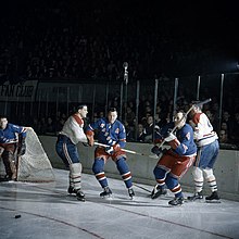 Five men playing hockey in a crowded arena.