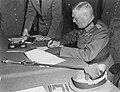 Image 19 German Instrument of Surrender Photograph credit: Lt. Moore; restored by Adam Cuerden The German Instrument of Surrender was the legal document that effected the termination of the Nazi regime and ended World War II in Europe. A July 1944 draft version had also included the surrender of the German government, but this was changed due to concern that there might be no functional German government that could surrender; instead, the document stated that it could be "superseded by any general instrument of surrender imposed by, or on behalf of the United Nations", which was done the next month. This photograph shows Field Marshal Wilhelm Keitel signing the German Instrument of Surrender in Berlin. The first surrender document was signed on 7 May 1945 in Reims by General Alfred Jodl, but this version was not recognized by the Soviet High Command and a revised version was required. Prepared in three languages on 8 May, it was not ready for signing in Berlin until after midnight; consequently, the physical signing was delayed until nearly 1:00 a.m. on 9 May, and backdated to 8 May to be consistent with the Reims agreement and public announcements of the surrender already made by Western leaders.