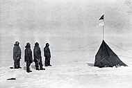 冰天雪地中，四个身穿厚重棉袄的人站在左侧，右侧是一个深色的帐篷，由若干绳索固定，帐篷上插着两面旗帜，上方是挪威国旗，下方是前进号船旗。