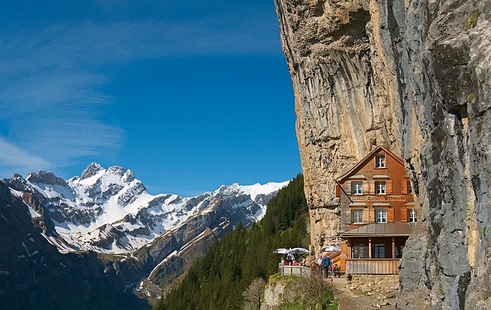 图为于瑞士内阿彭策尔州维尔德基希利洞穴（英语：Wildkirchli）的小路上，建于山崖中的埃舍尔山旅馆（Berggasthof Aescher）。该建筑物主立面的景色尤其著名。