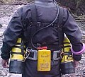Yellow battery canister for caving head light carried on back of sidemount harness.