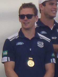 Selwood wearing sunglasses and premiership medal, standing in front of another member of the team