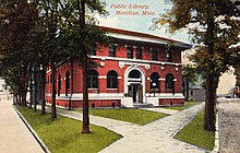 Postcard depicting a red-bricked library building surrounded by trees with the text "Public Library, Meridian, Miss."