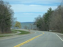 A two-lane highway surrounded by trees and following the St Lawrence river.