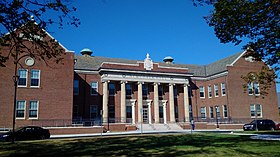 large brick building with six tall columns having Ionic capitals at the center entrance