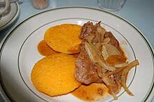 Round, yellow cakes topped with fried meat and onions.