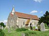 A stone church with red tiled roofs, showing the nave and aisle beside each other, a small spire, and the south porch