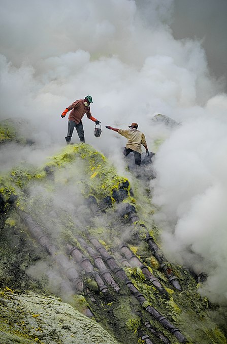 图为印尼爪哇岛东部伊真火山的传统硫黄开采。图中所示的是矿工所面对既危险又崎岖的地况，他们要面对的还有毒烟、高空坠落和缺乏保护装备。他们所站位置的管道用于引导及凝结硫蒸汽，以便生产（最起码相对容易一些）。