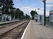 A set of two tram tracks between two platforms with shelters.