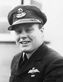 Smiling young man with rounded face wearing full dress military uniform and cap, suit and tie.