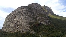 Ridge of a mountain seen in low angle with a cave at its base.