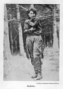 A woman in buckskins, Anahareo, holds a beaver in her arms.