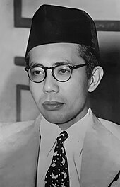 A man in spectacles and a songkok, looking left