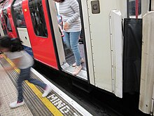 people stepping over a large gap between an Underground train and a train platform