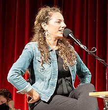Sona Movsesian speaking into a microphone on stage at the Alberta Rose Theater in Portland, Oregon in September 2022.