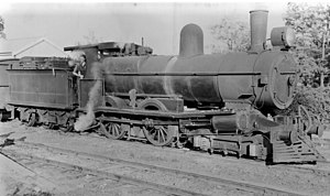 A class 4-4-0 steam engine stopped at a railway station.