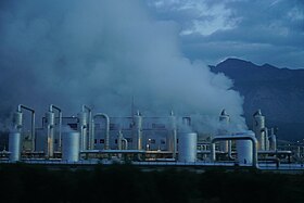 Steaming pipes and cylinders with mountains in the far background