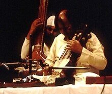 Narayan and another man perform on a platform.