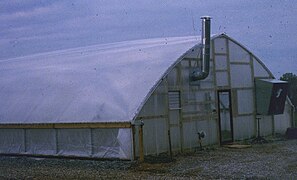 Air-inflated double polyethylene cover on quonset greenhouse with heater and ventilation fan.