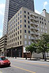 Ground-level view of an 8-story building with a tan brick facade.