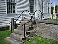 Stone steps over cemetery wall, with iron railing