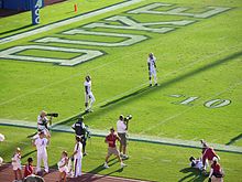 A pair of players wait at the end zone for a kickoff.