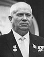 An elderly bald man in a suit, with several medals pinned on it