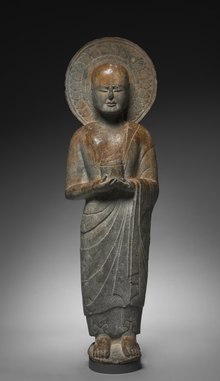 Monk holding cylinder-shaped object. Monk is depicted with aura-like shape around the head
