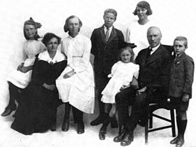 Family photo with six children and two seated adults