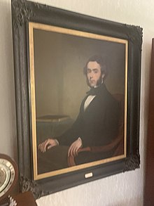 Colour oil painting of George Vause Birks seated, wearing black jacket, white shirt and black cravat