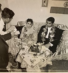 A dressed-up young couple, sitting on a love seat