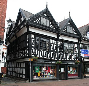 A black-and-white building in a corner position, with two gables to the front and three to the side.